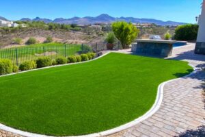 Artificial Turf Lawn Installed By Green America Tree &Amp; Landscaping In A Las Vegas Backyard With Clean Curved Edging And Desert Landscaping.
