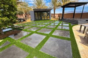 Close-Up Of Artificial Turf Installed By Green America Tree &Amp; Landscaping In Las Vegas, Showing Clean Edging Between Turf, Pavers, And Decorative Landscape Rock.