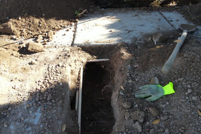 A Hole Dug To Repair An Irrigation System, With The Irrigation Pipes Exposed.